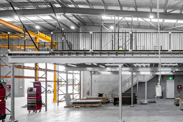 interior of a warehouse with a mezzanine level scaffolding and storage areas featuring orange overhead cranes and tools for construction 4 storage solutions 4 productivity 4 safety