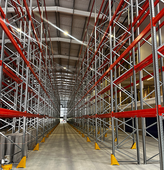 wide warehouse aisle with metal shelving and red brackets designed for efficient storage solutions and organizing inventory 4 shelving units
